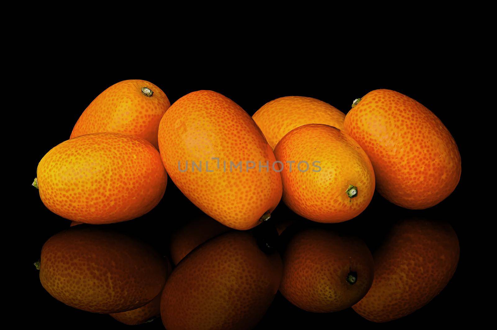 Heap of ripe kumquats on black background with reflection