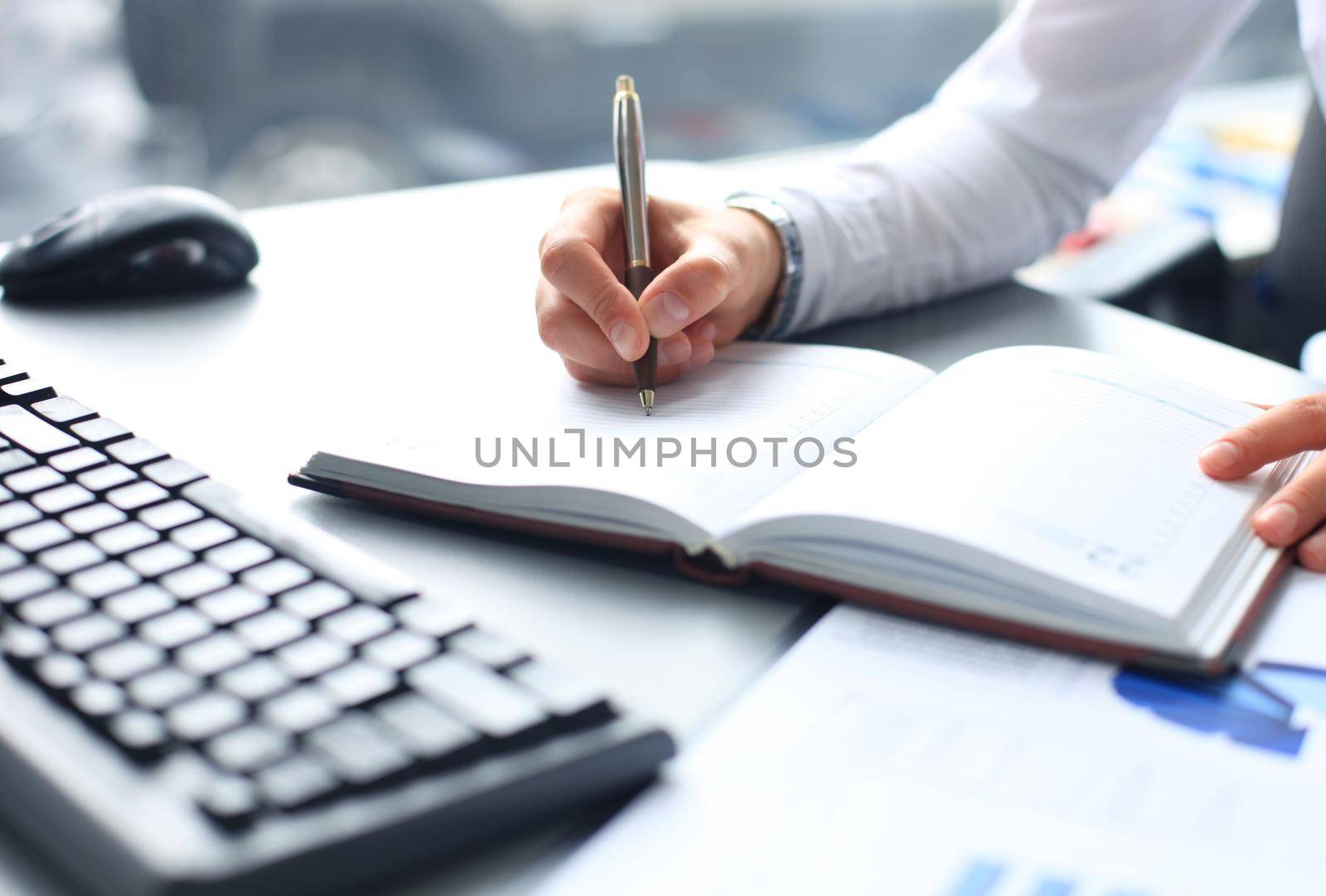 Businesswoman makes a note in notebook.