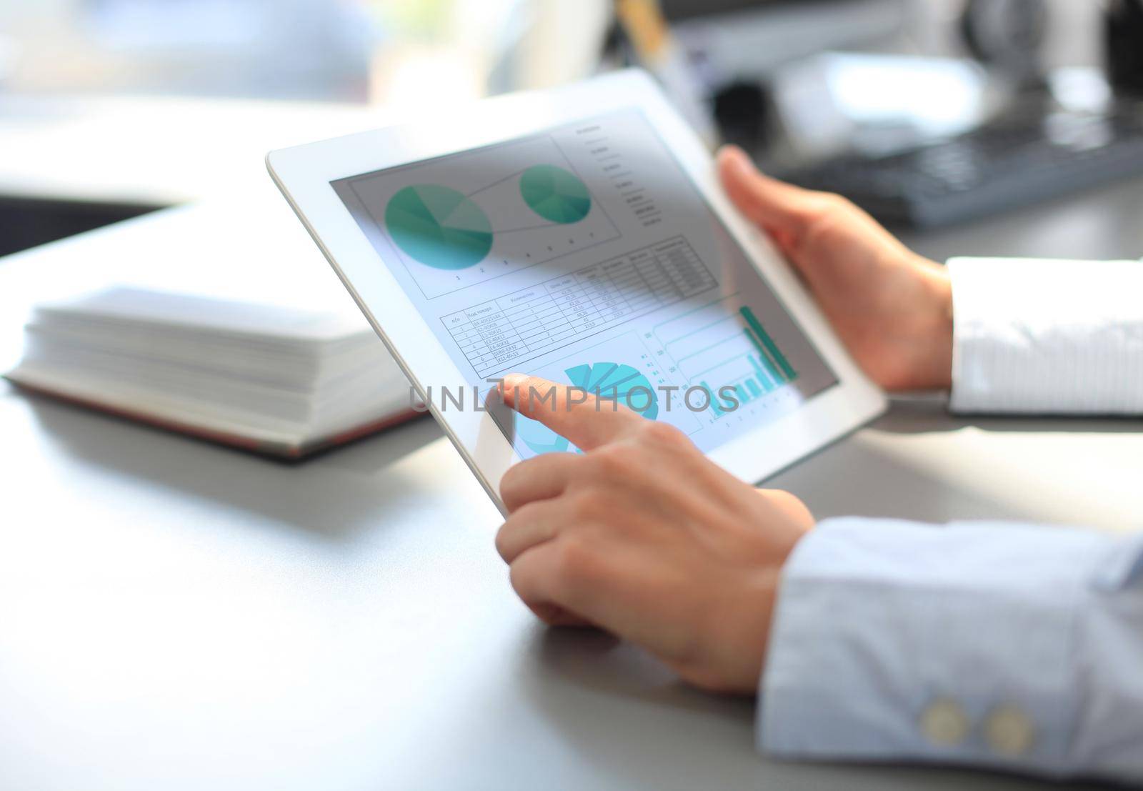 Business person analyzing financial statistics displayed on the tablet screen by tsyhun