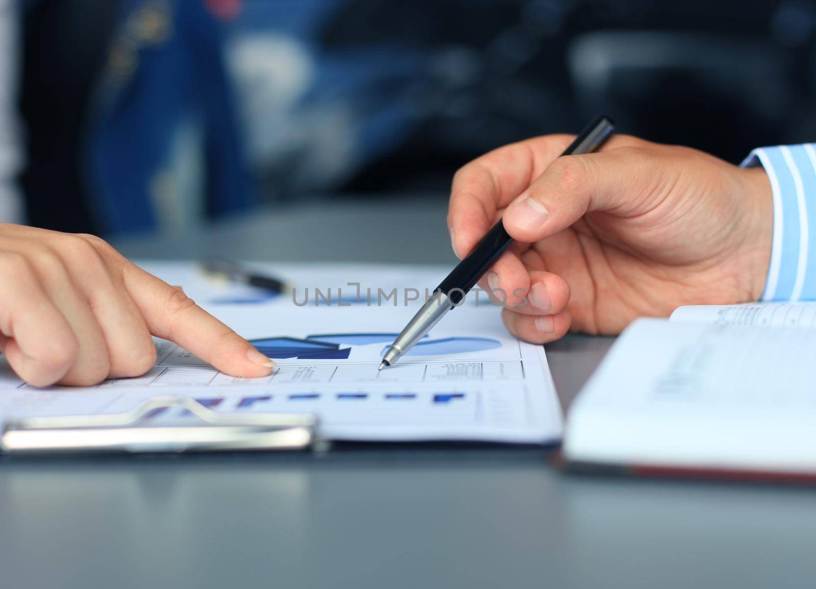 Unrecognizable business person analyzing graphs and taking notes by tsyhun