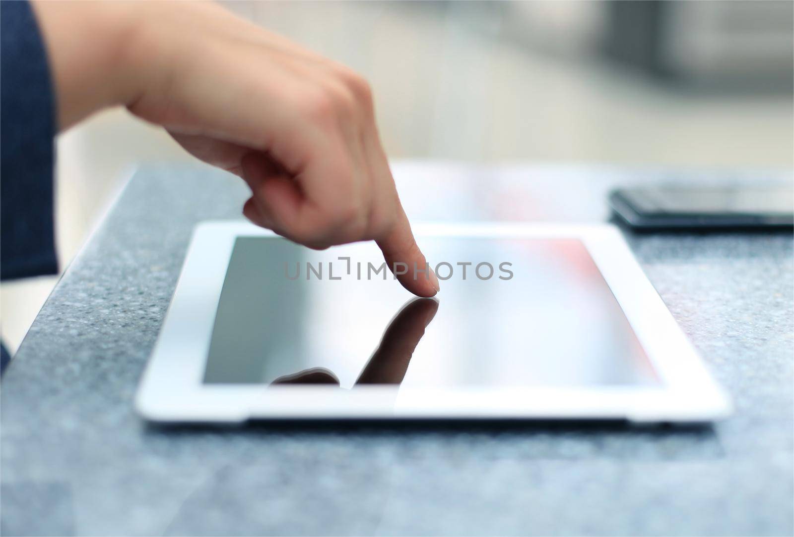 Woman hand touching screen on modern digital tablet pc. Close-up image with shallow depth of field focus on finger.
