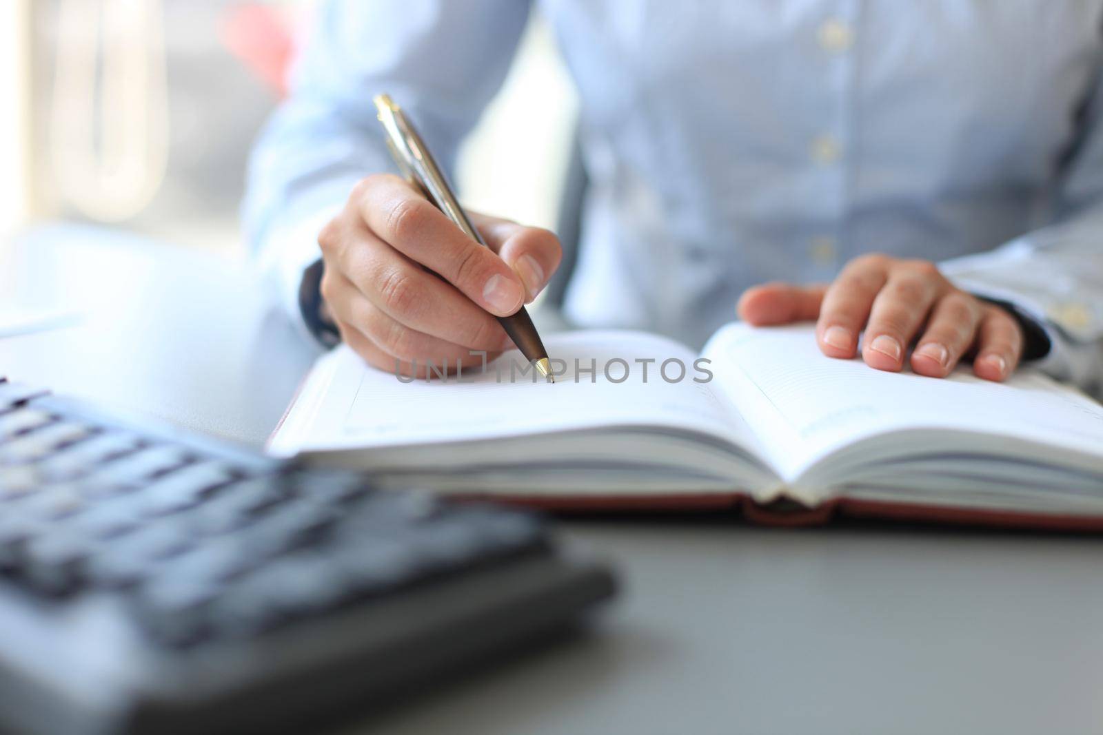 businessman writes in a notebook while sitting at a desk by tsyhun