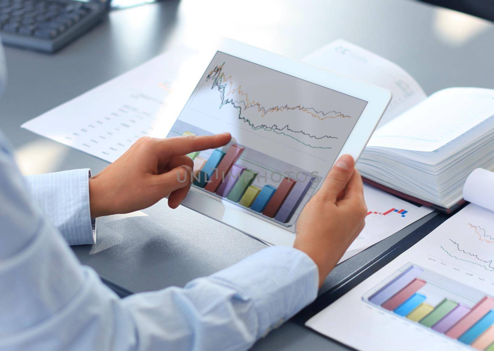 Business person analyzing financial statistics displayed on the tablet screen