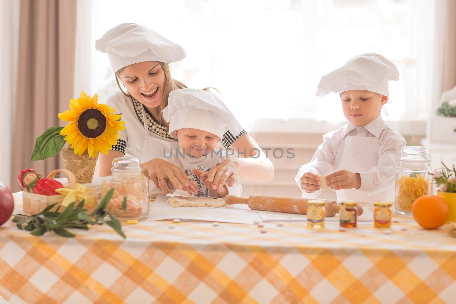 Happy mother and her child in the form of cooks prepare lunch, play with each other