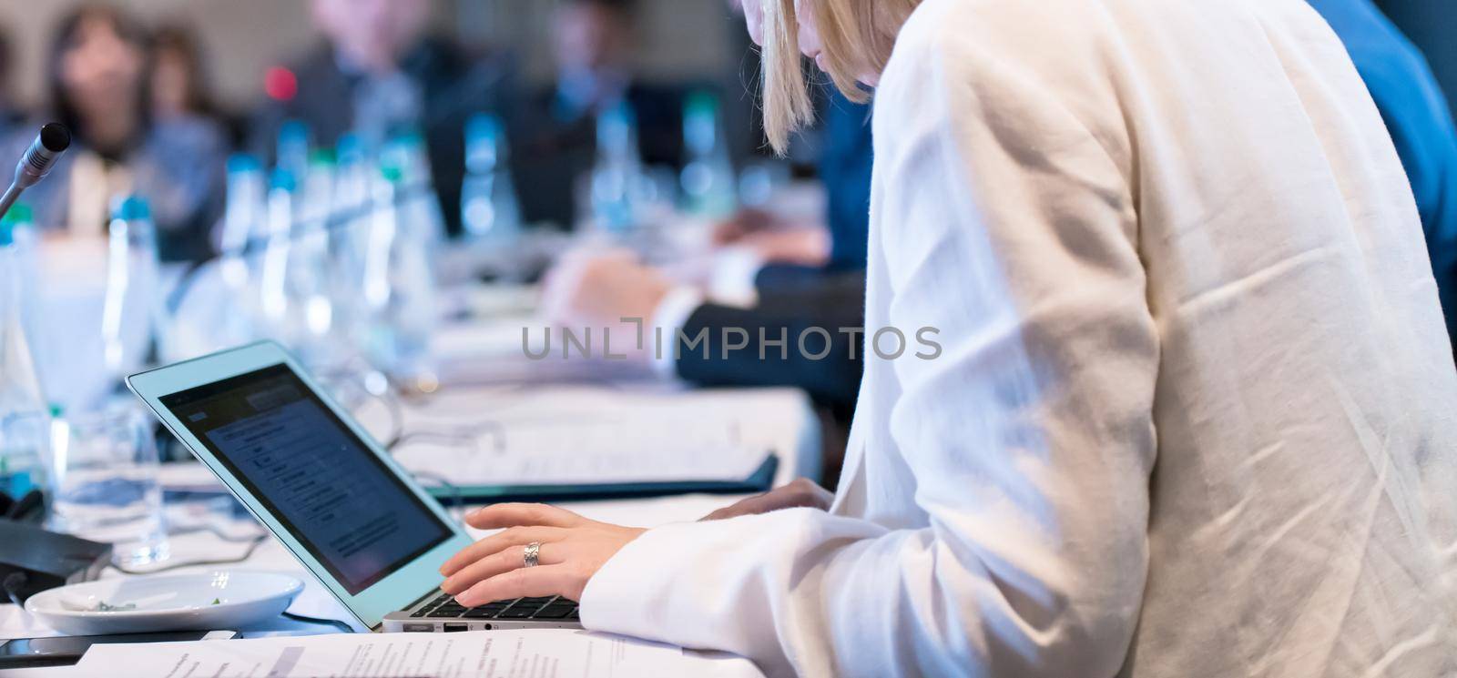 close up shot of business people hands typing on laptop computer keyboard during the business seminar at big modern conference room