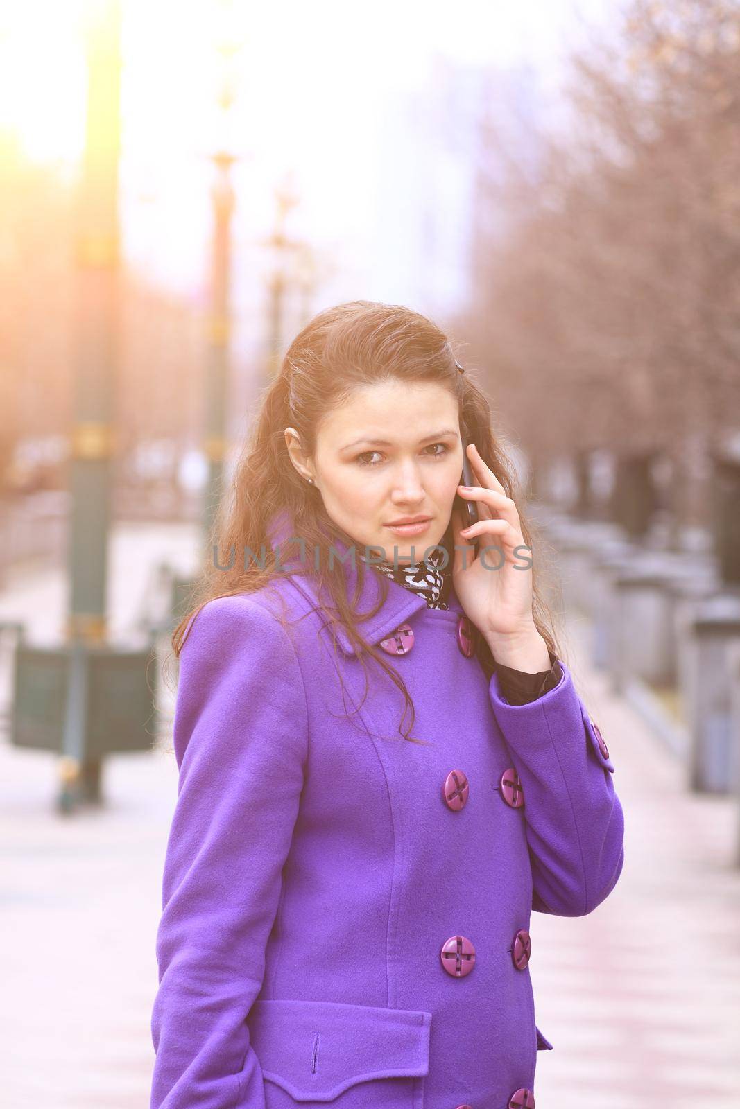 Beautiful girl talking on the phone outside in the park in autumn