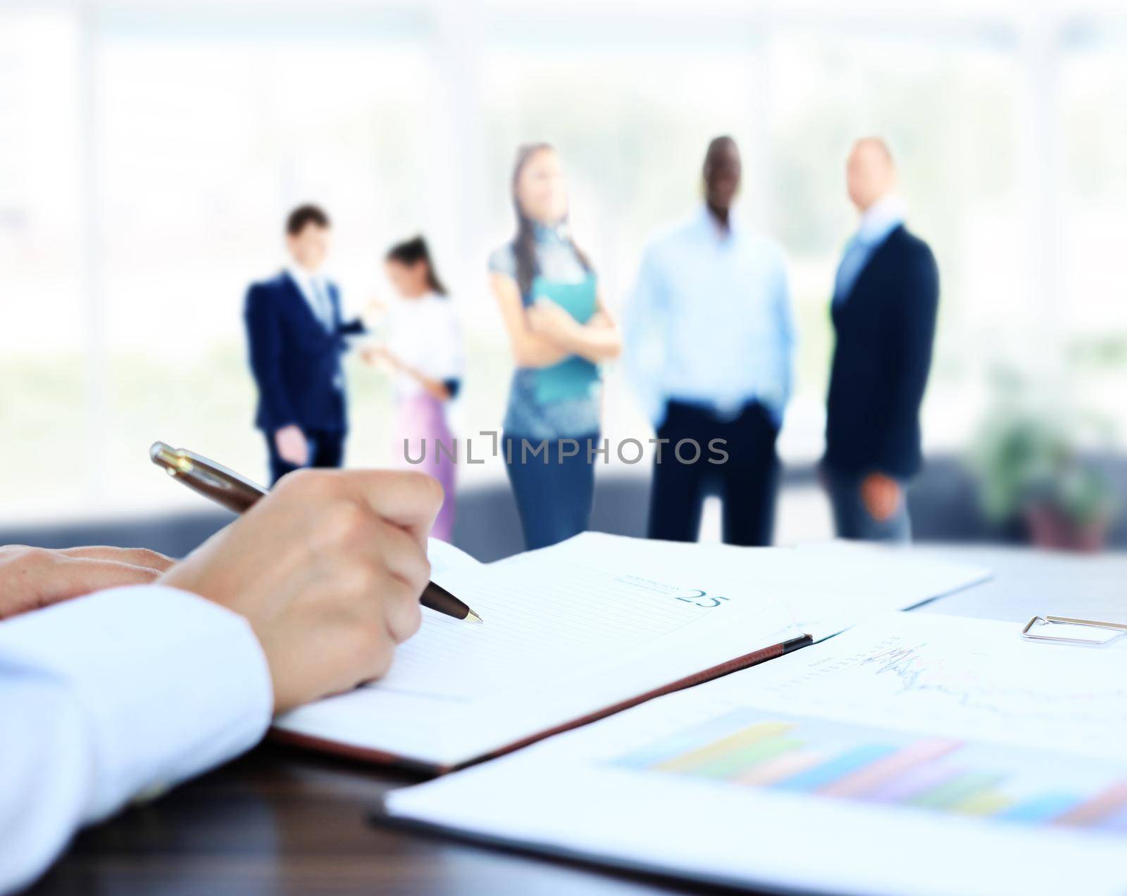 businessman writes in a notebook while sitting at a desk