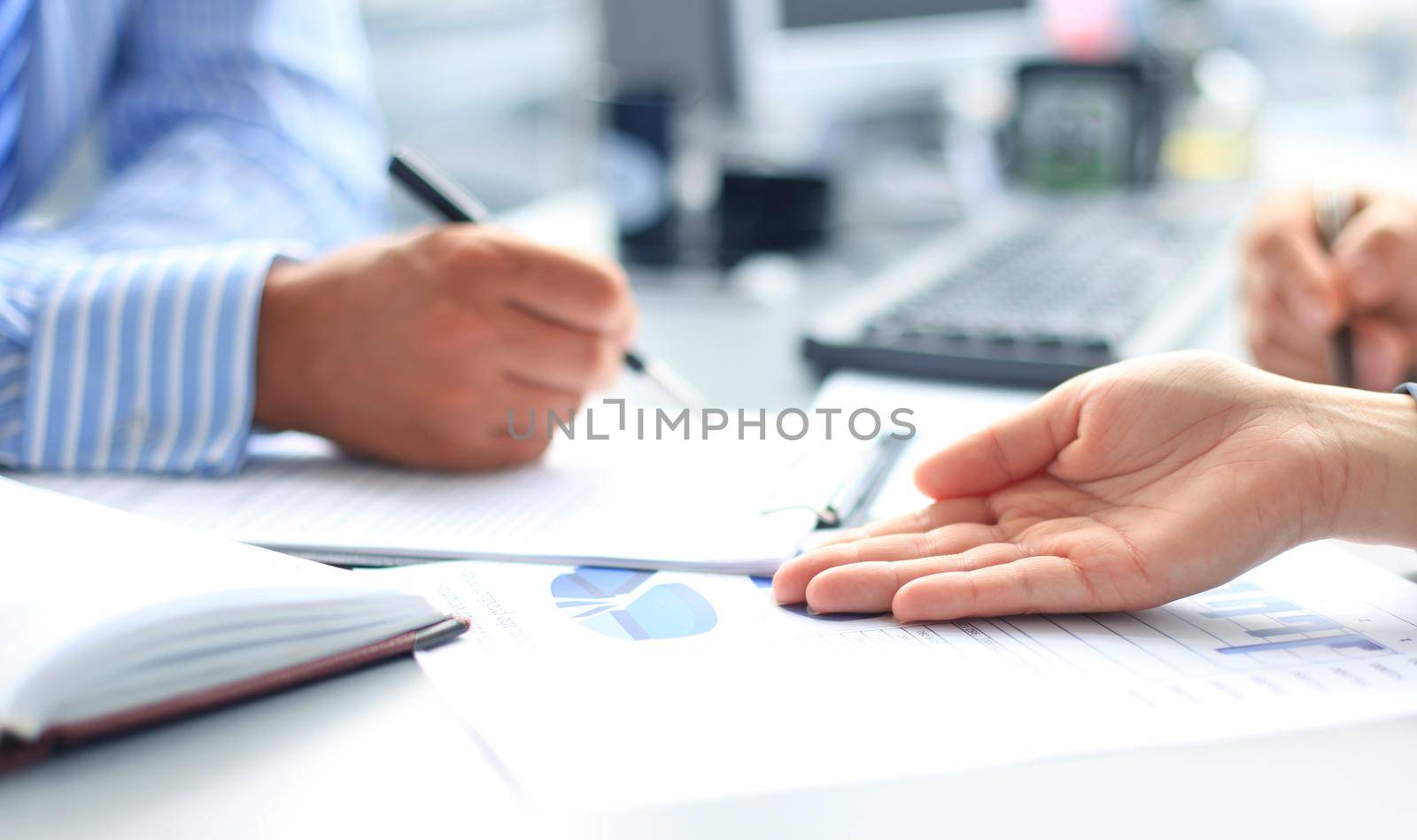 Unrecognizable business person analyzing graphs and taking notes