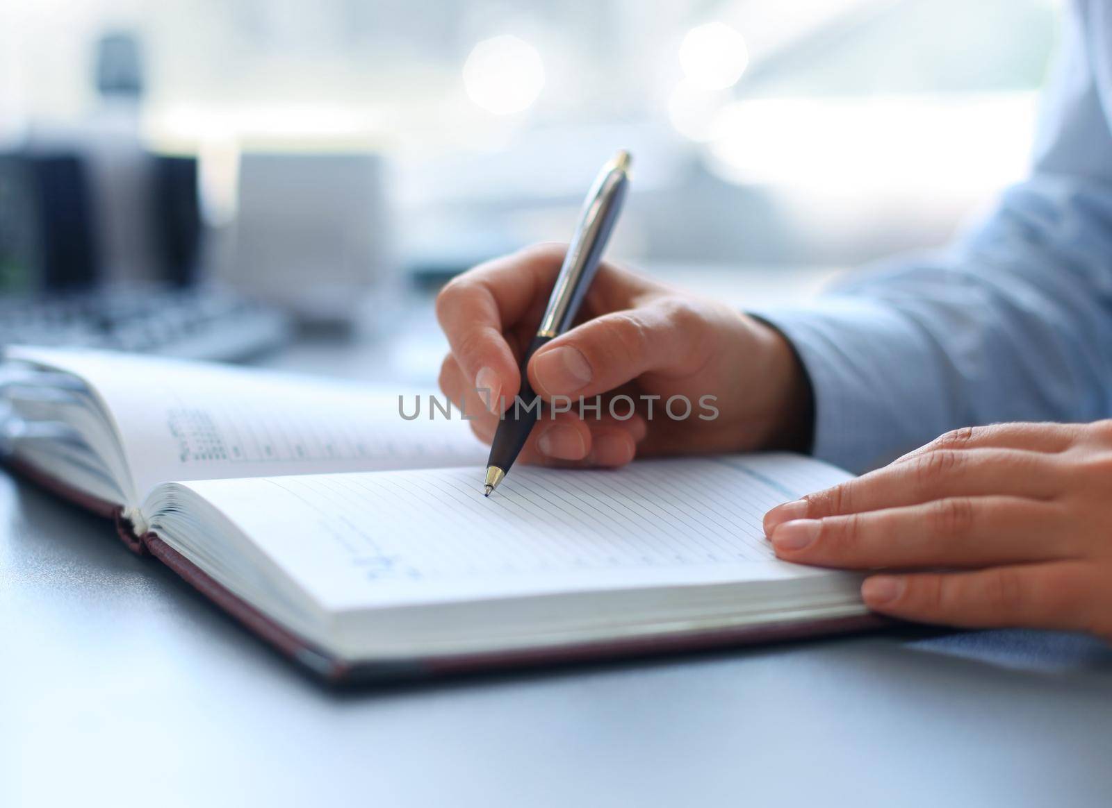 Businesswoman makes a note in notebook.