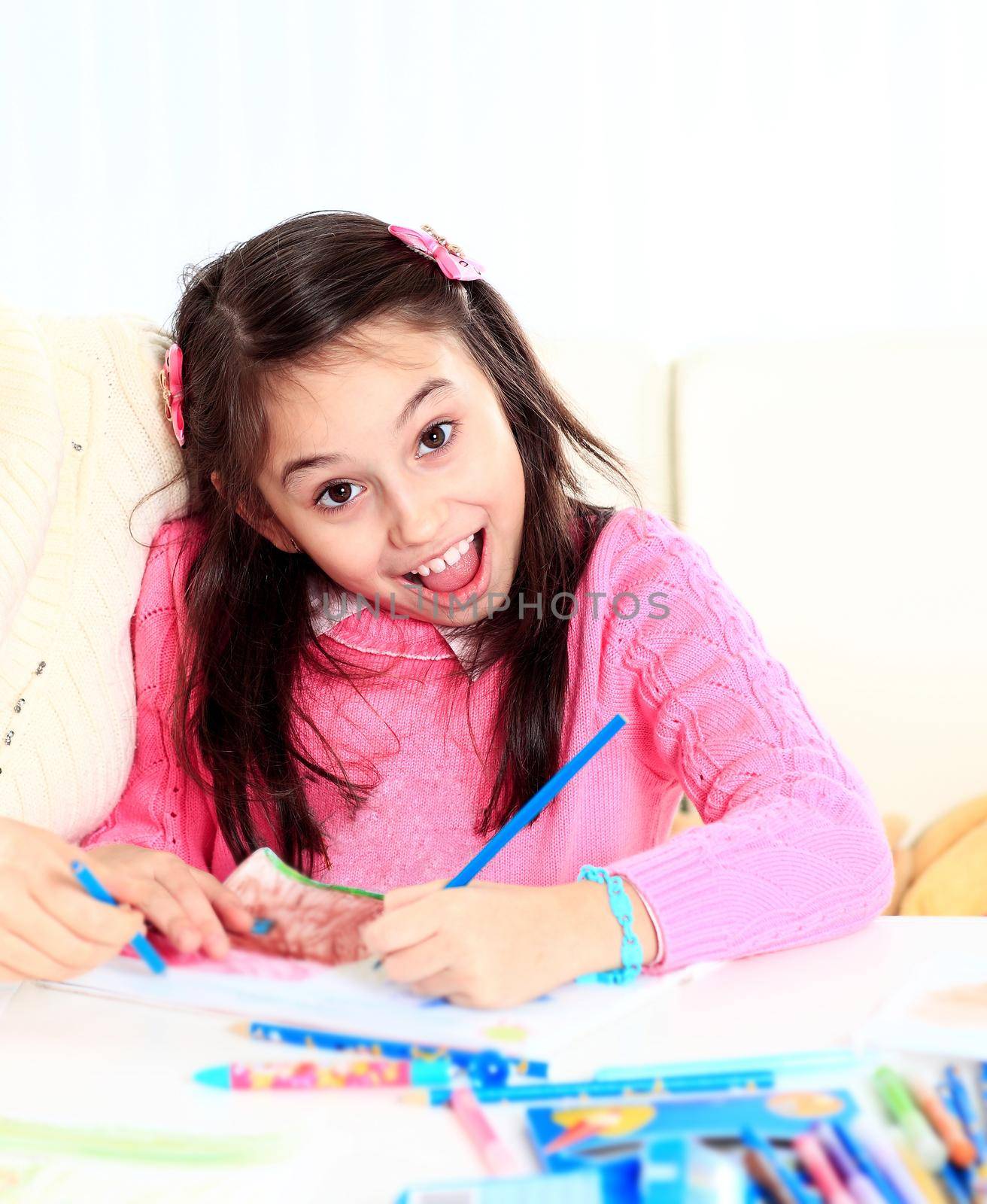 Beautiful girl draws with crayons and markers with surprise and joy on her face