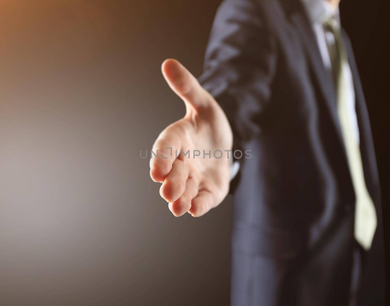 Business man with an open palm ready to strike a deal on a black background