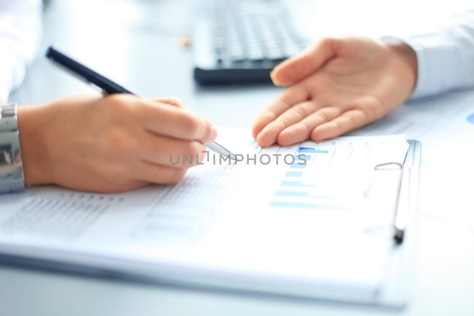 Unrecognizable business person analyzing graphs and taking notes by tsyhun