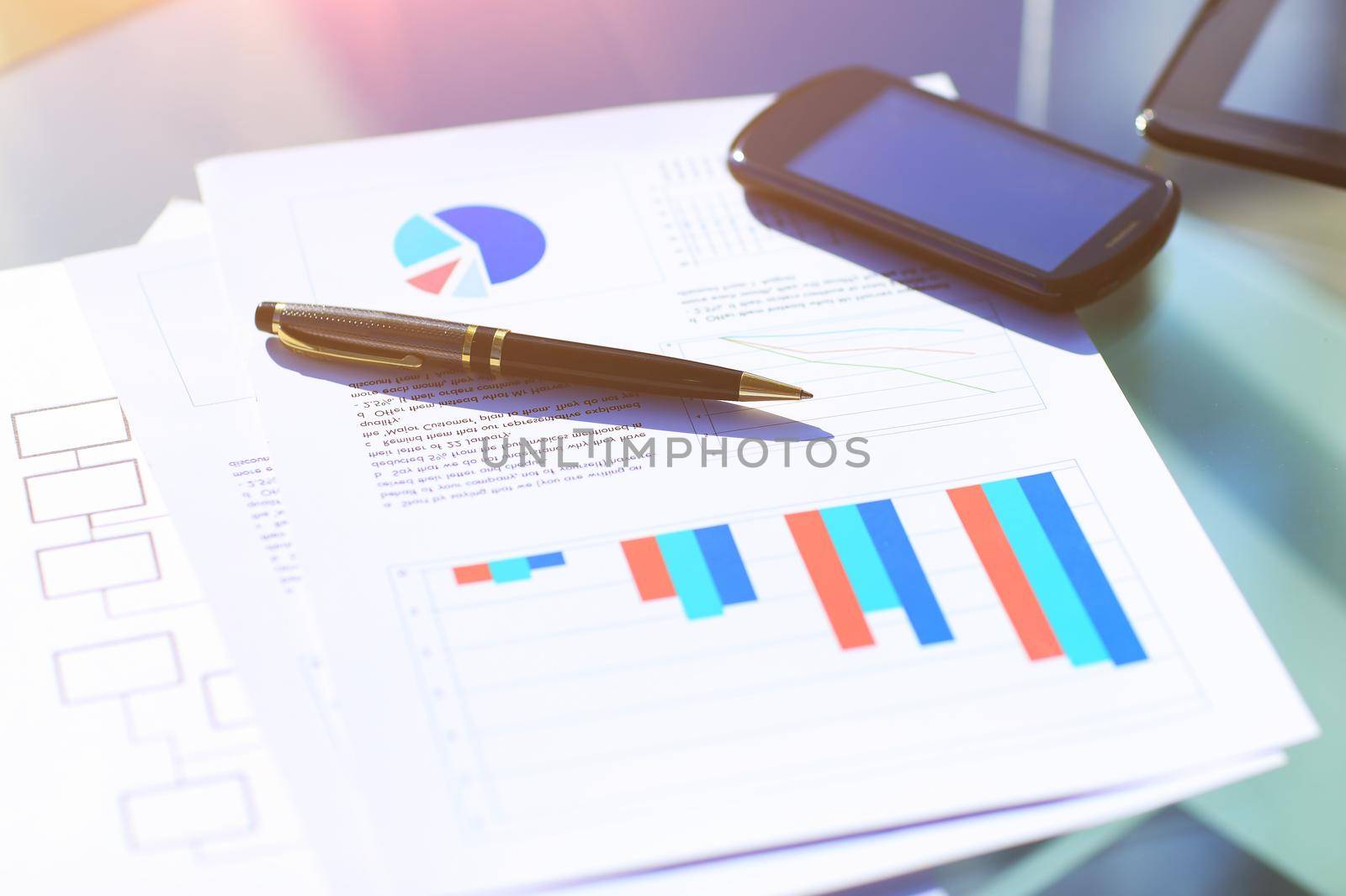 Financial charts on the table with tablet and pen in office