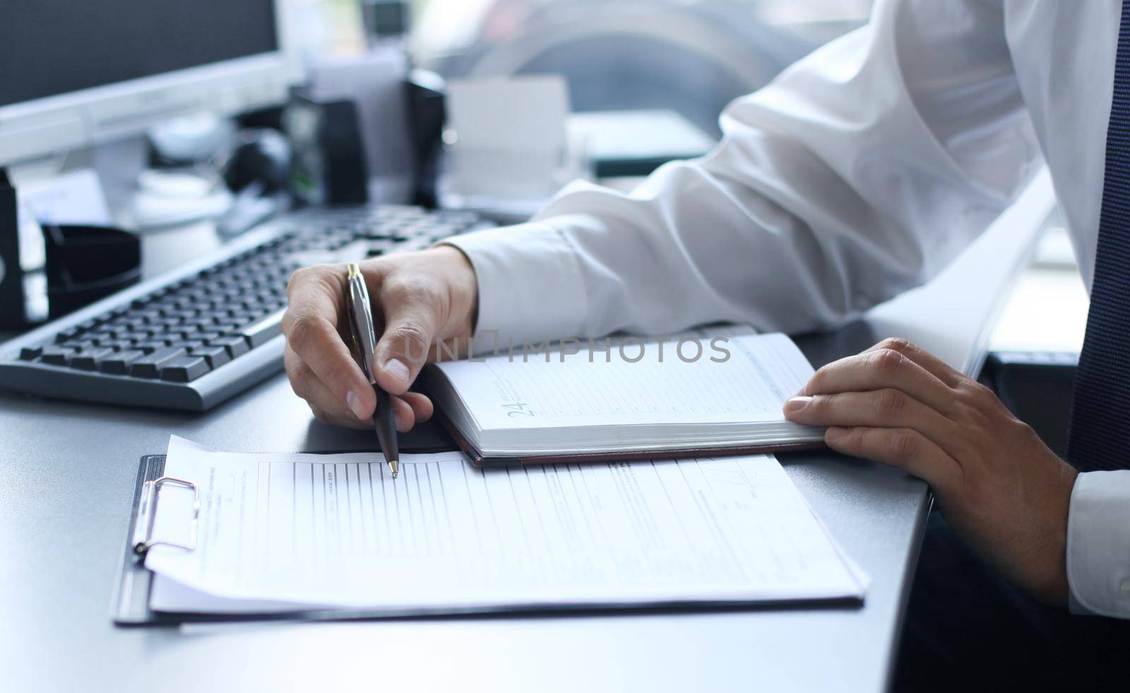 businessman writes in a notebook while sitting at a desk