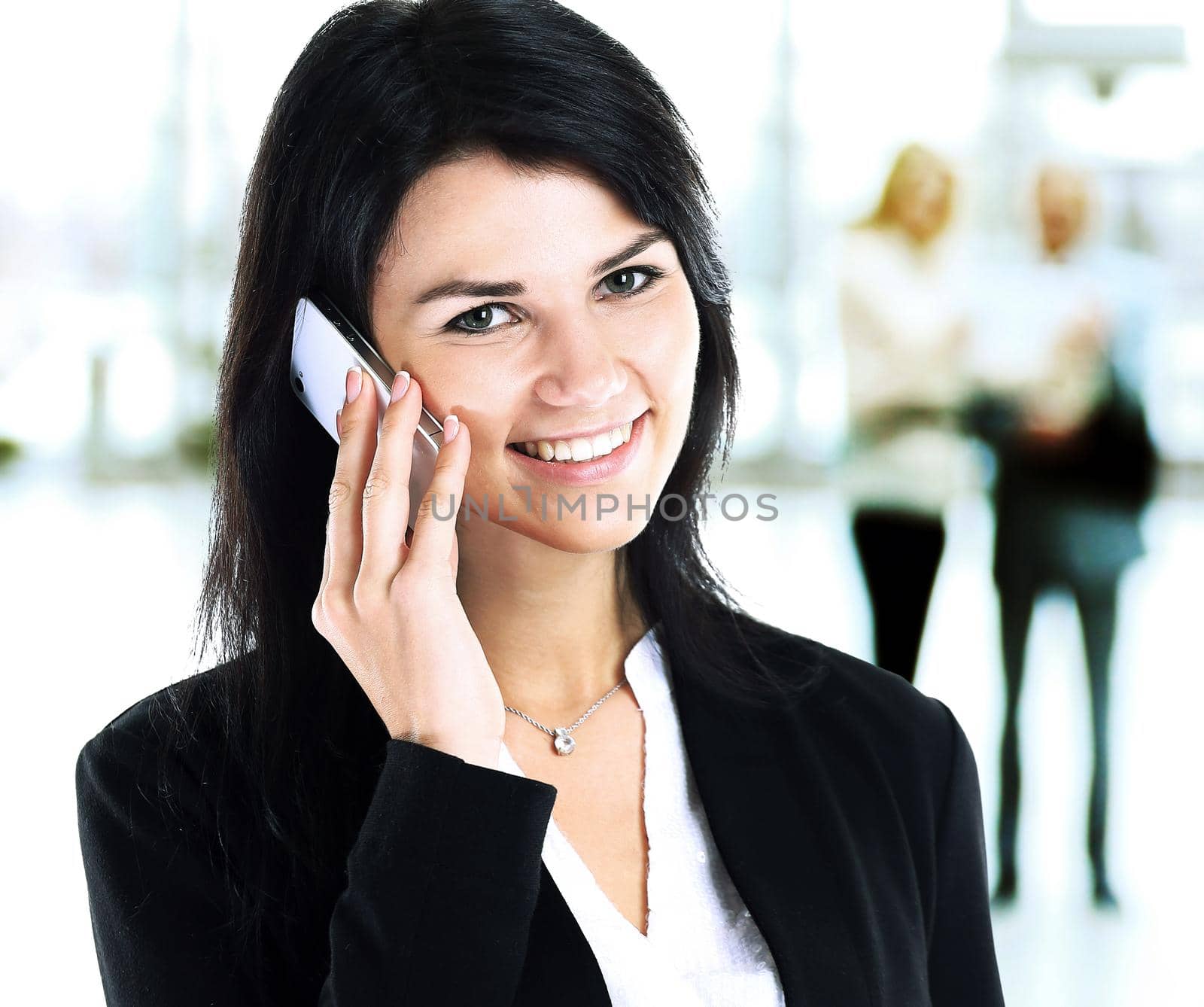 Business girl talking on the phone in the background of their team in the office