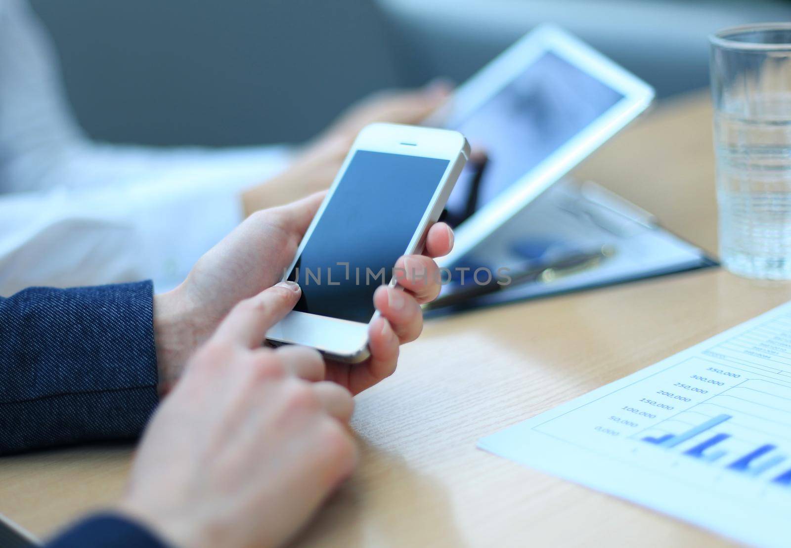 Smartphone handheld in closeup, colleagues working in background. by tsyhun