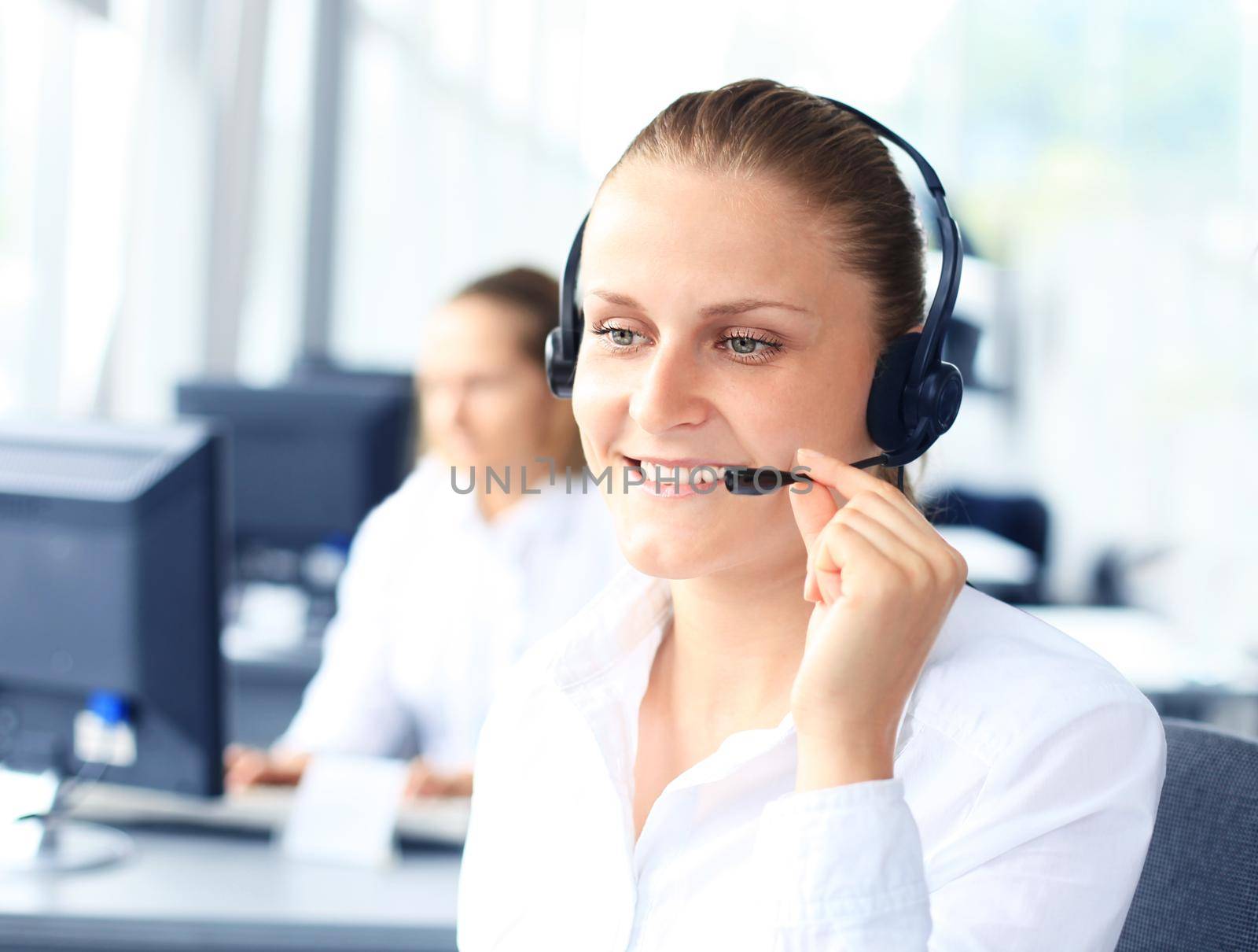 Beautiful young female call center operator with headset in office by tsyhun