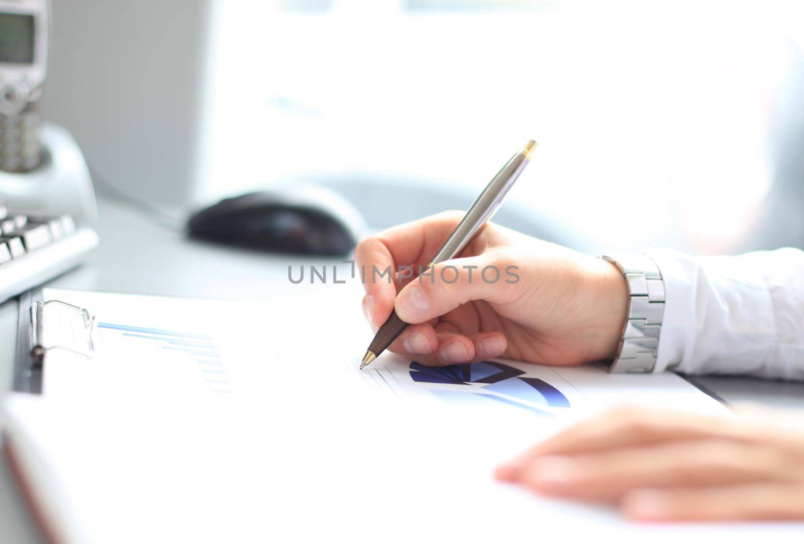 Unrecognizable business person analyzing graphs and taking notes by tsyhun