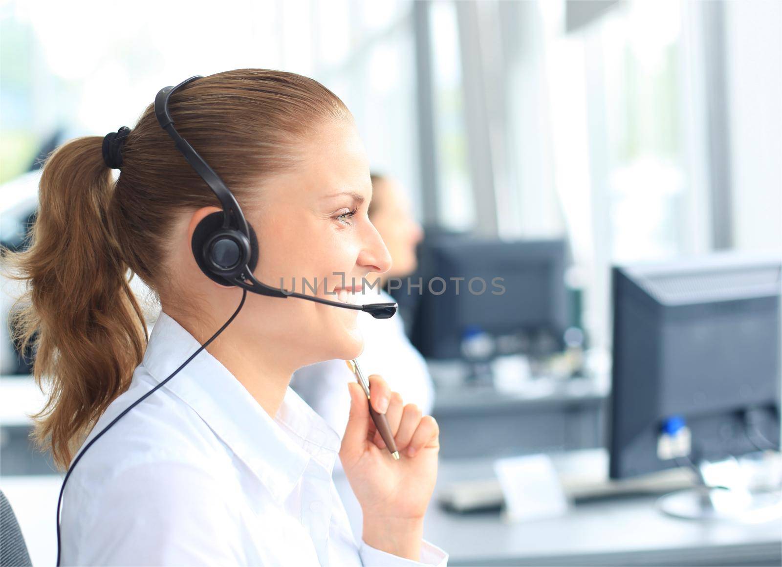 Beautiful young female call center operator with headset in office