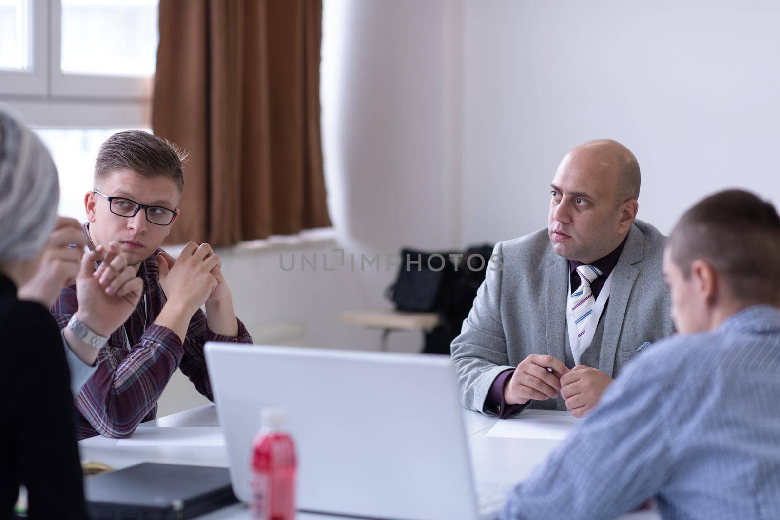 Group of a young business people brainstorming and discussing business plan on meeting at startup office interior