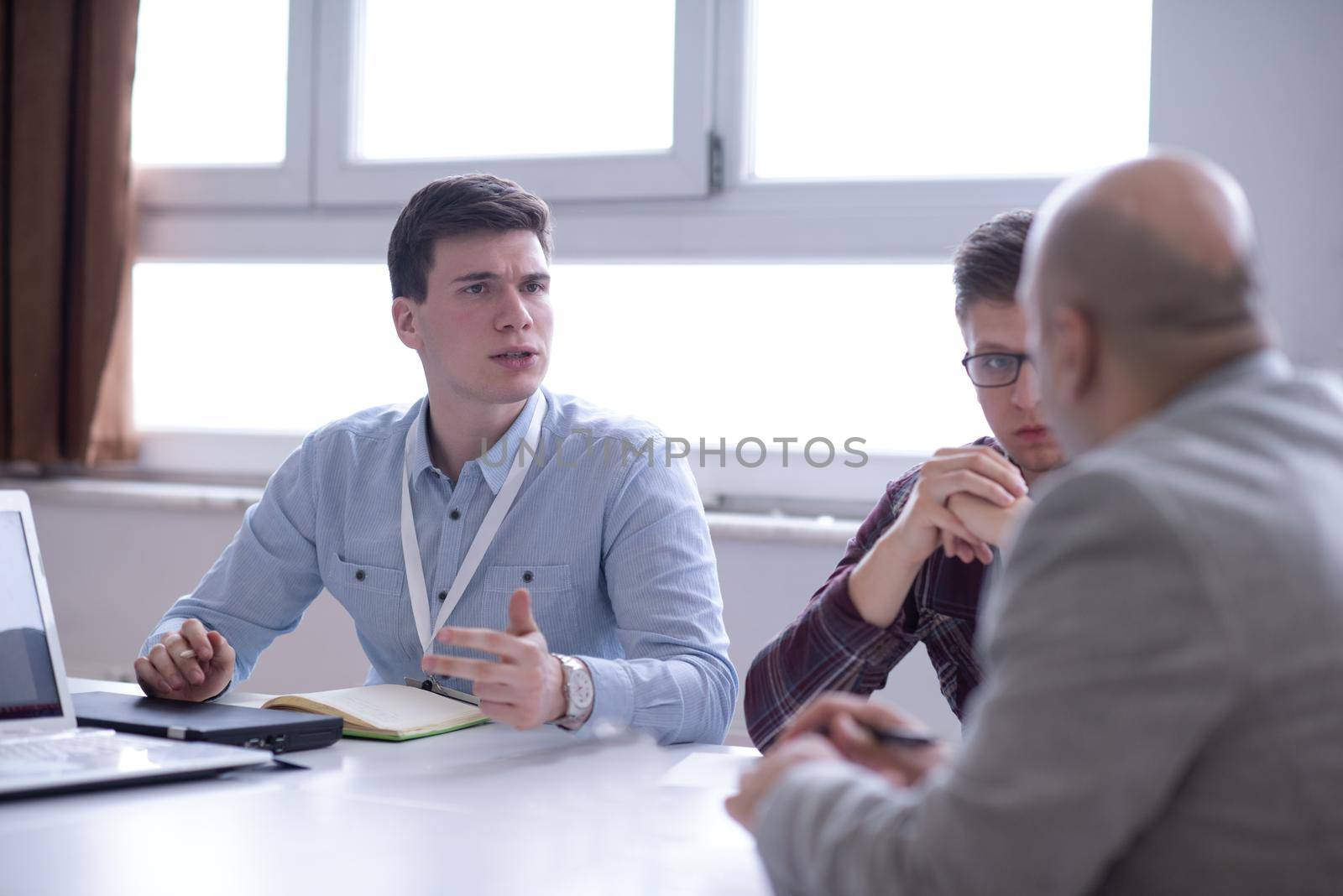 Group of a young business people brainstorming and discussing business plan on meeting at startup office interior