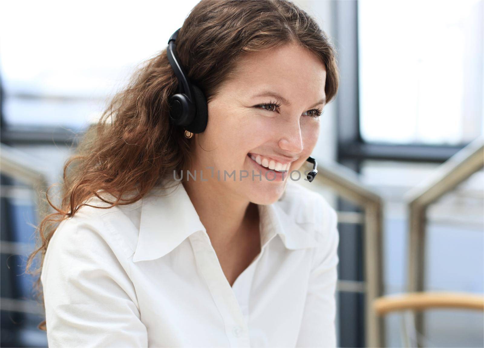 Beautiful young female call center operator with headset in office