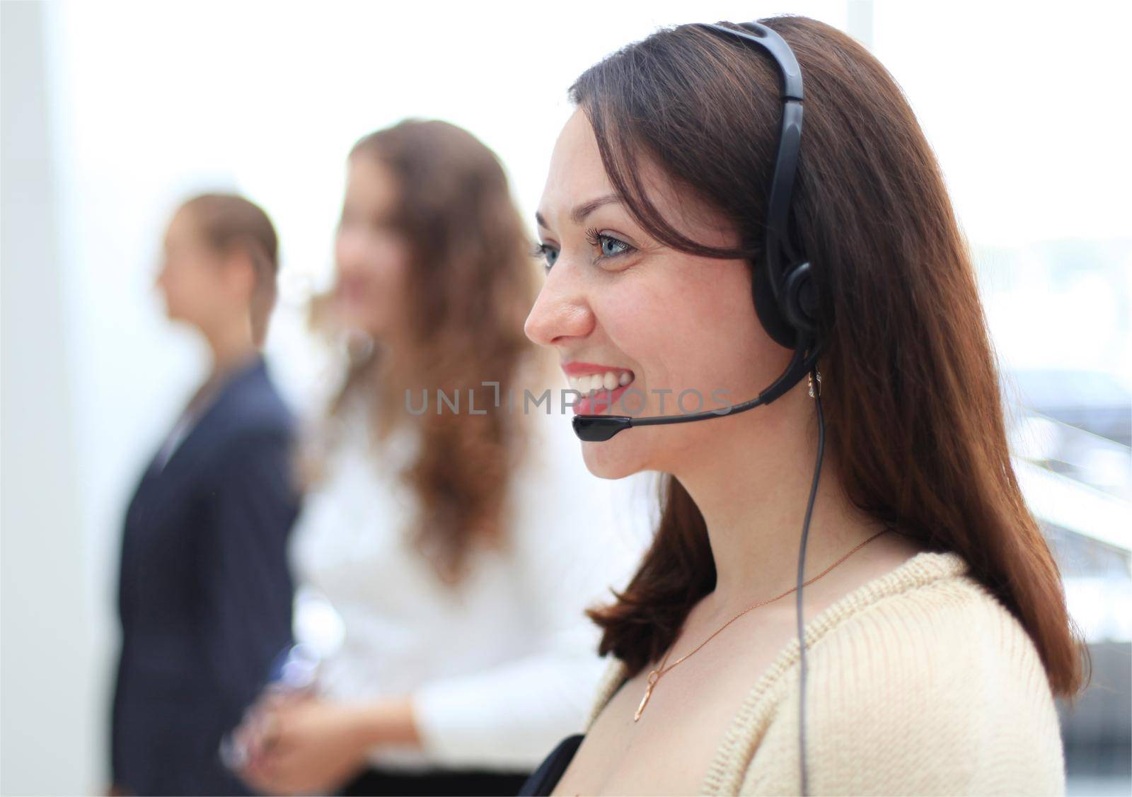 Young employee working with a headset and accompanied by her team by tsyhun