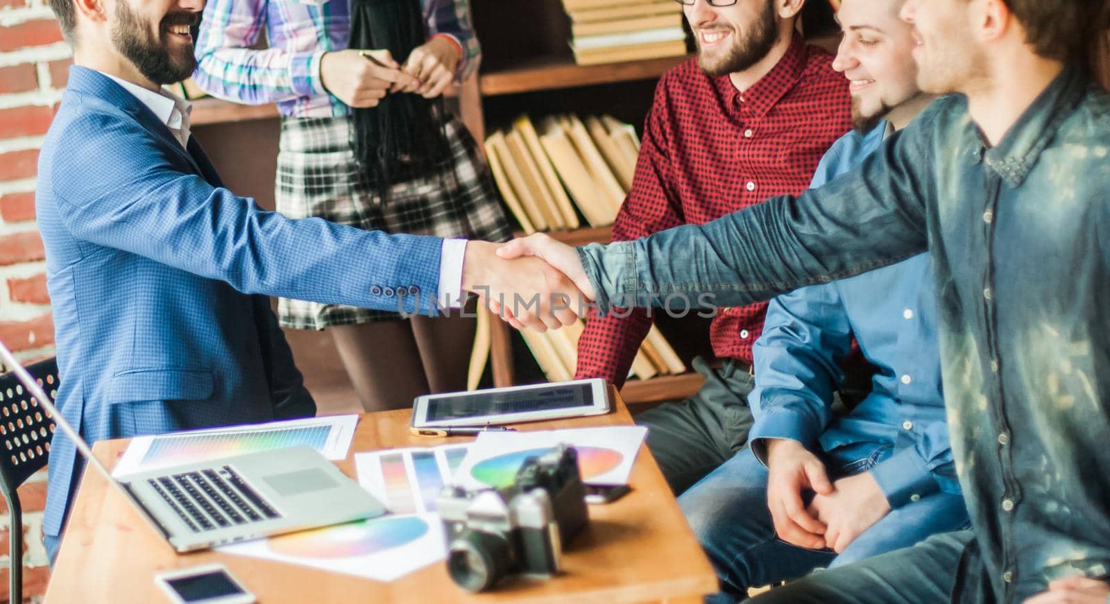 handshake business partners at a meeting in creative office on the background of business team