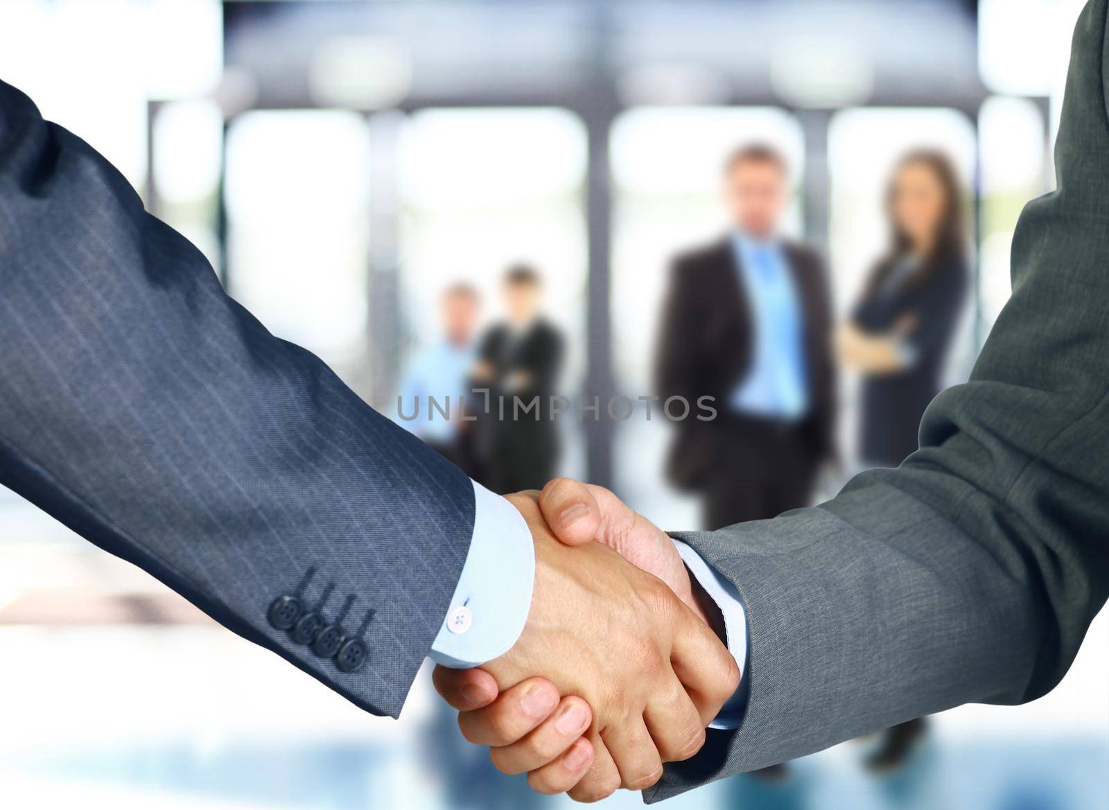 Business associates shaking hands in office by tsyhun