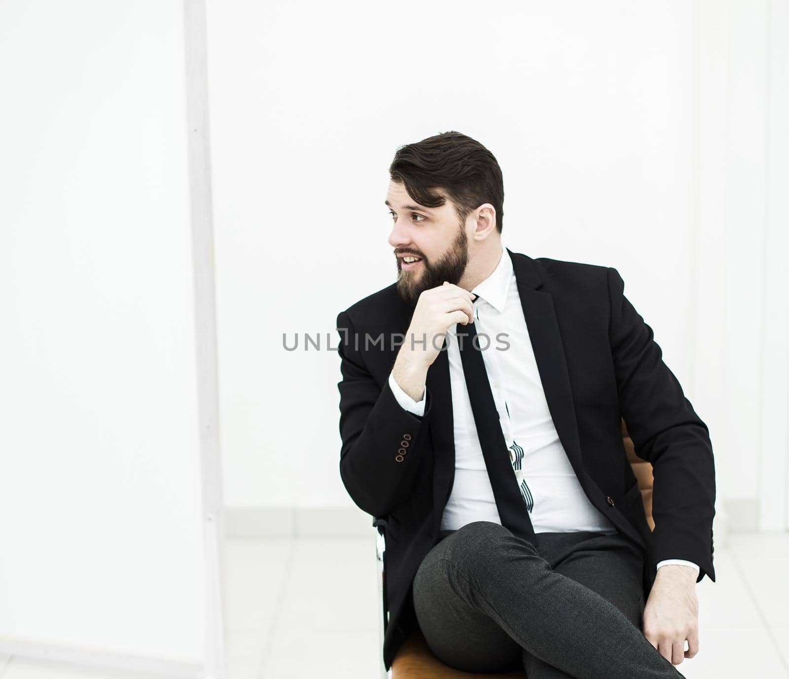 businessman in a business suit sitting on office chair on a light background. the photo has a empty space for your text.