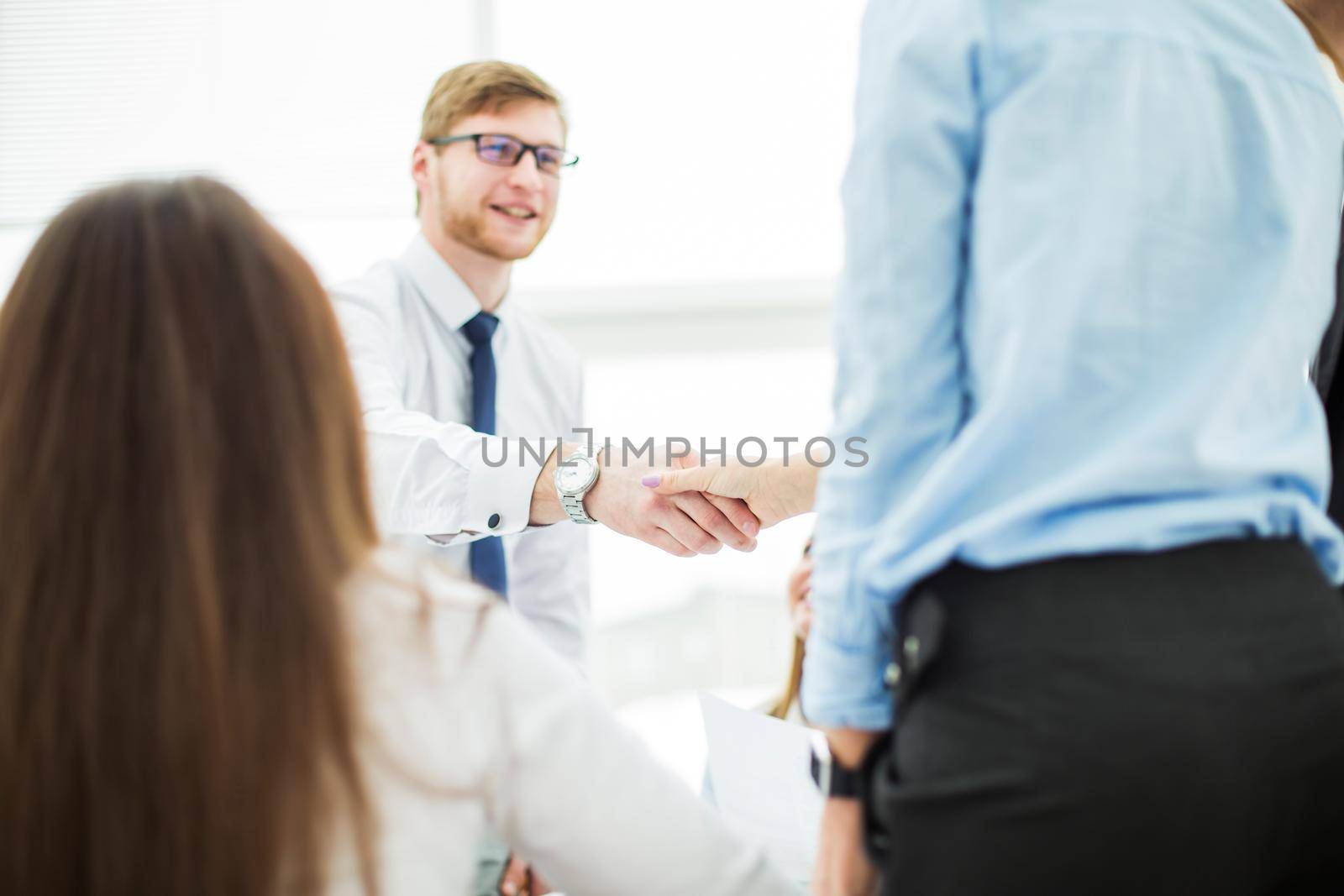 Bank Manager and the customer shake hands after signing a lucrative contract on the background of the modern office