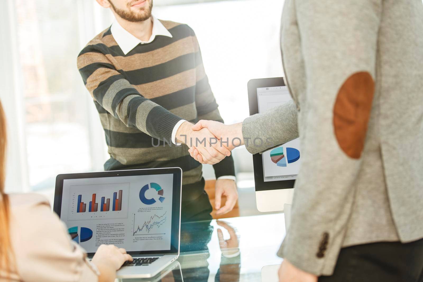 handshake between the client and the Manager of the company near the workplace in the modern office.