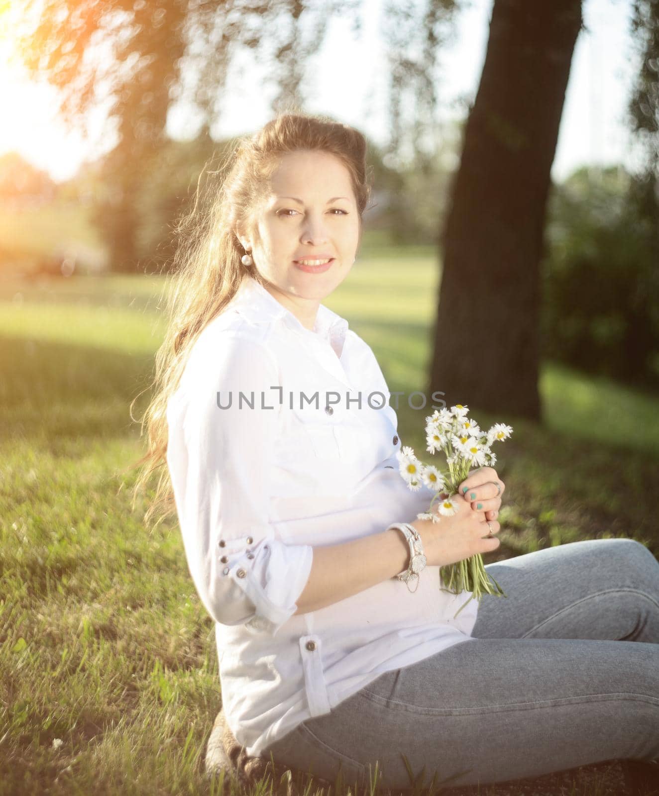 pregnant young woman with a bouquet of wildflowers in the Park on a Sunny day