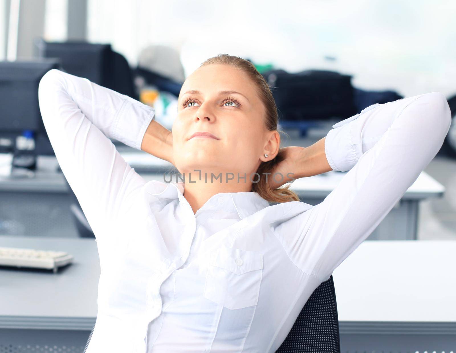 Business woman is relaxing with her hands behind her head and sitting on a chair in office by tsyhun