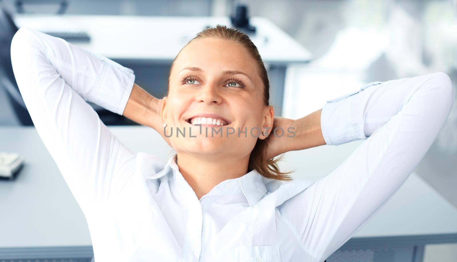 Business woman is relaxing with her hands behind her head and sitting on a chair in office