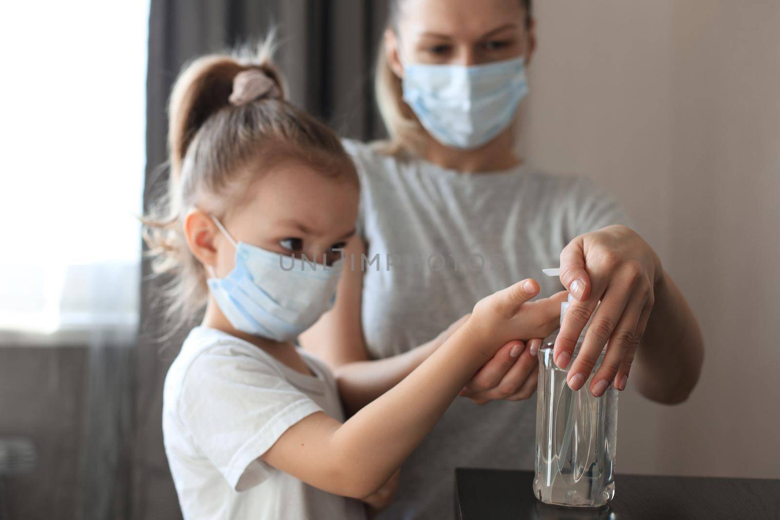 Mother and little daughter washing hand with alcohol sanitizer, prevent the virus and bacterias of Covid-19