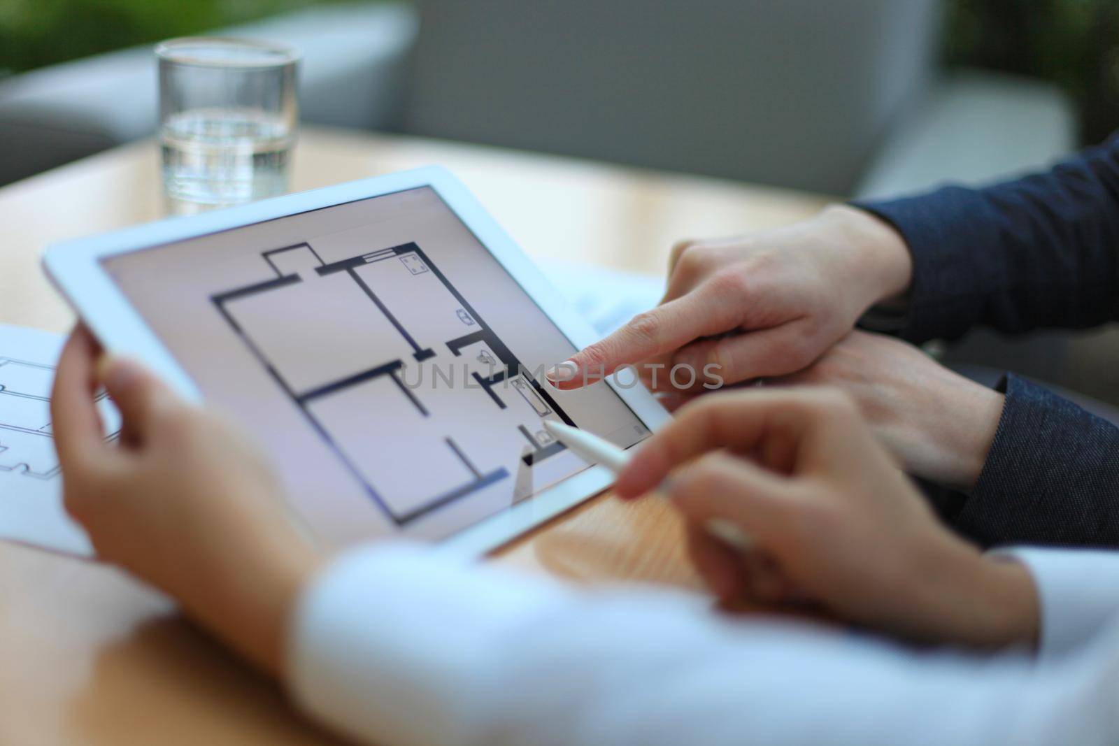 Real-estate agent showing house plans on electronic tablet by tsyhun