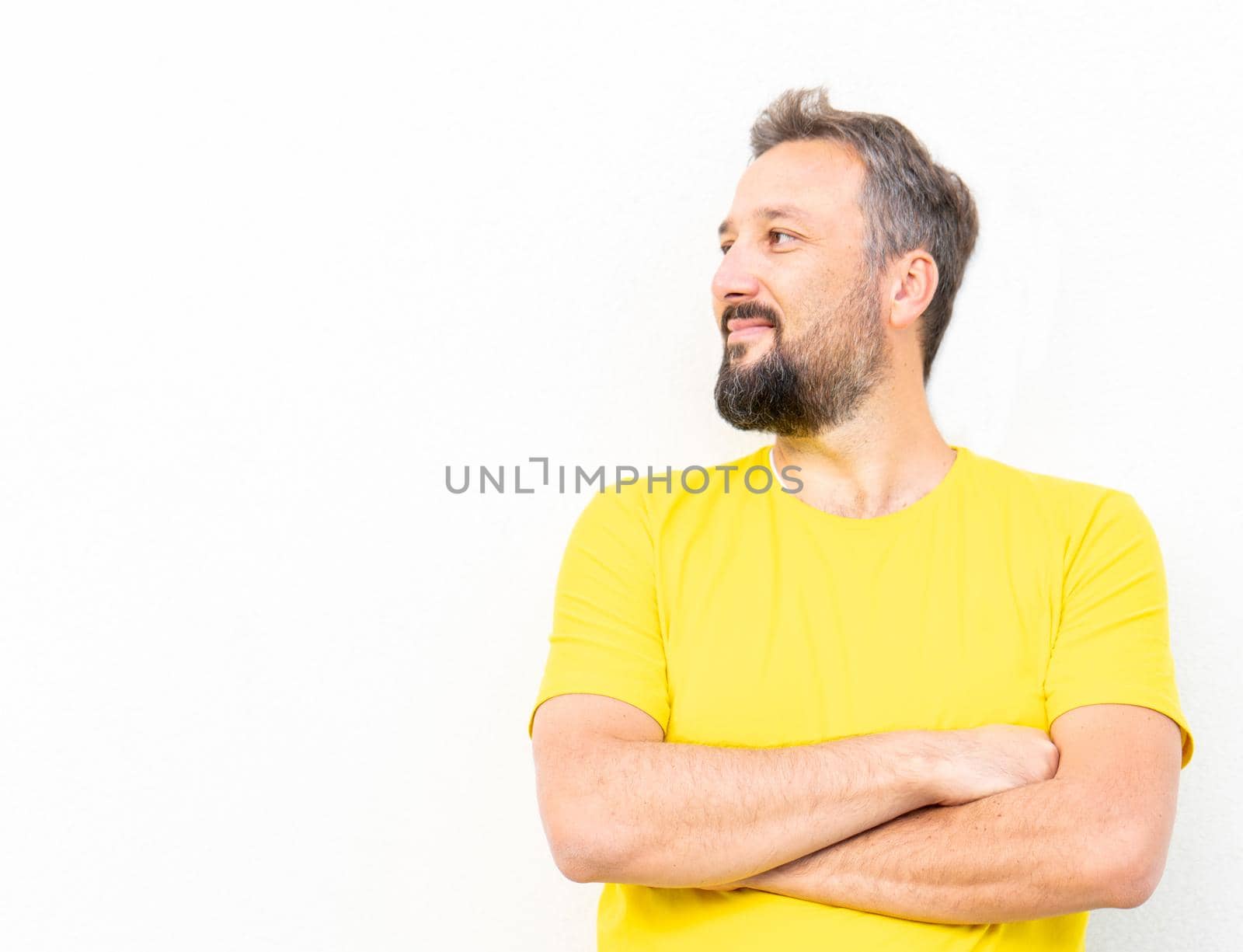 One positive man with yellow shirt portrait against wall