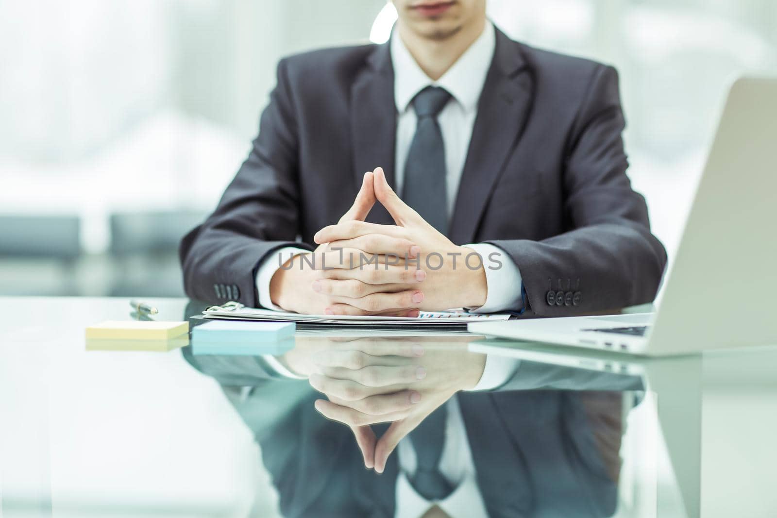 close-up of a successful businessman sitting behind a Desk, hands folded in front of him