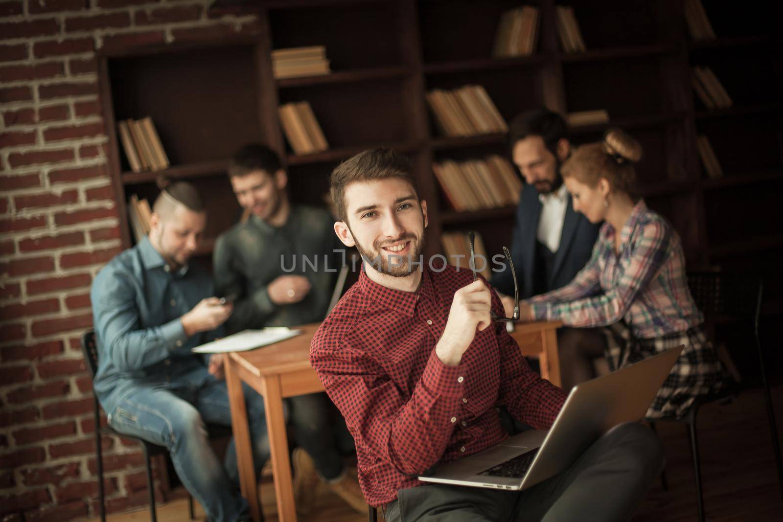 in the foreground the successful employee of the company with laptop on the background of business team