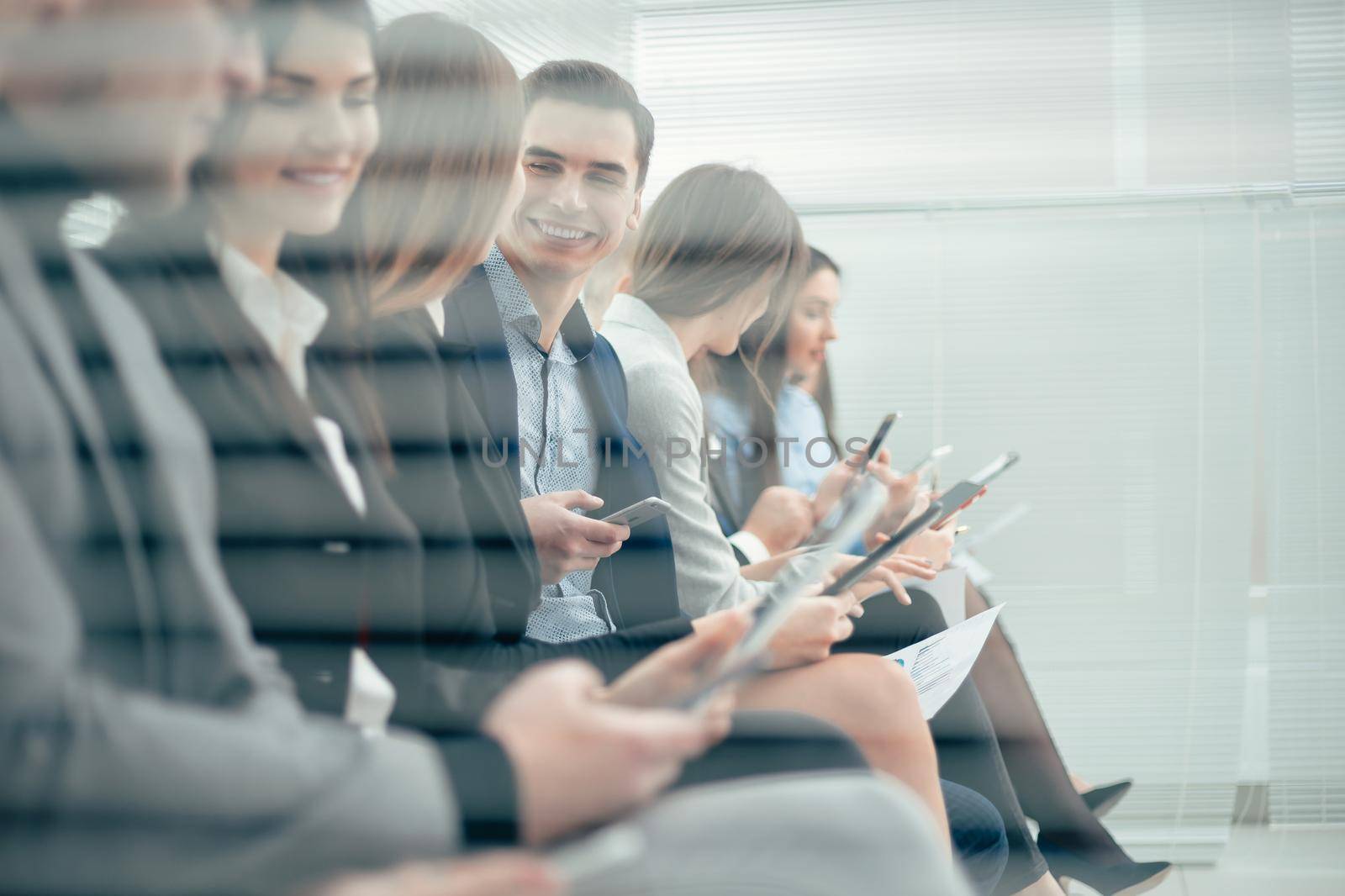 group of young candidates with questionnaires sitting in the office corridor by SmartPhotoLab