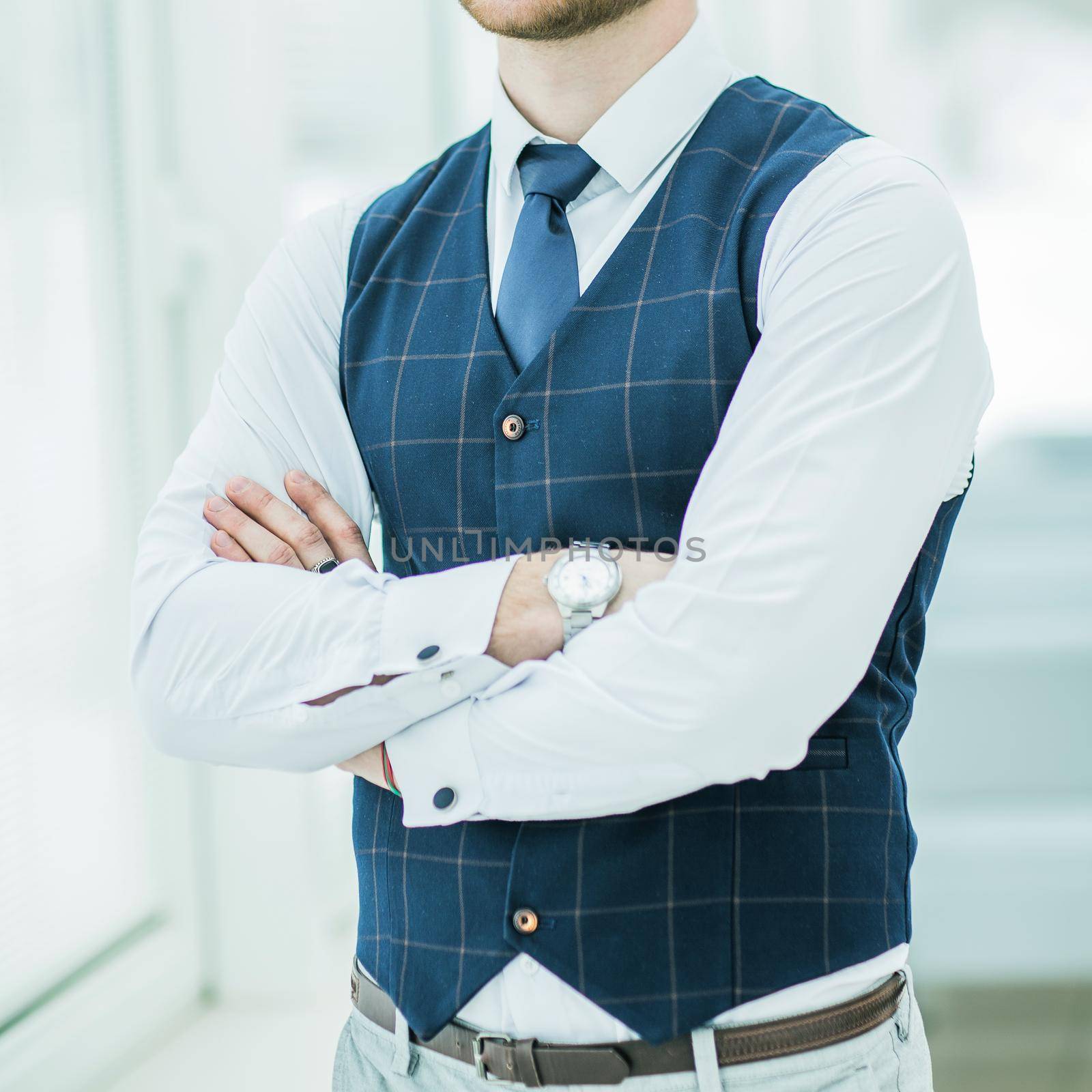 closeup of a thoughtful beginner businessman standing near window with hands clasped in front of him.the photo has a empty space for your text