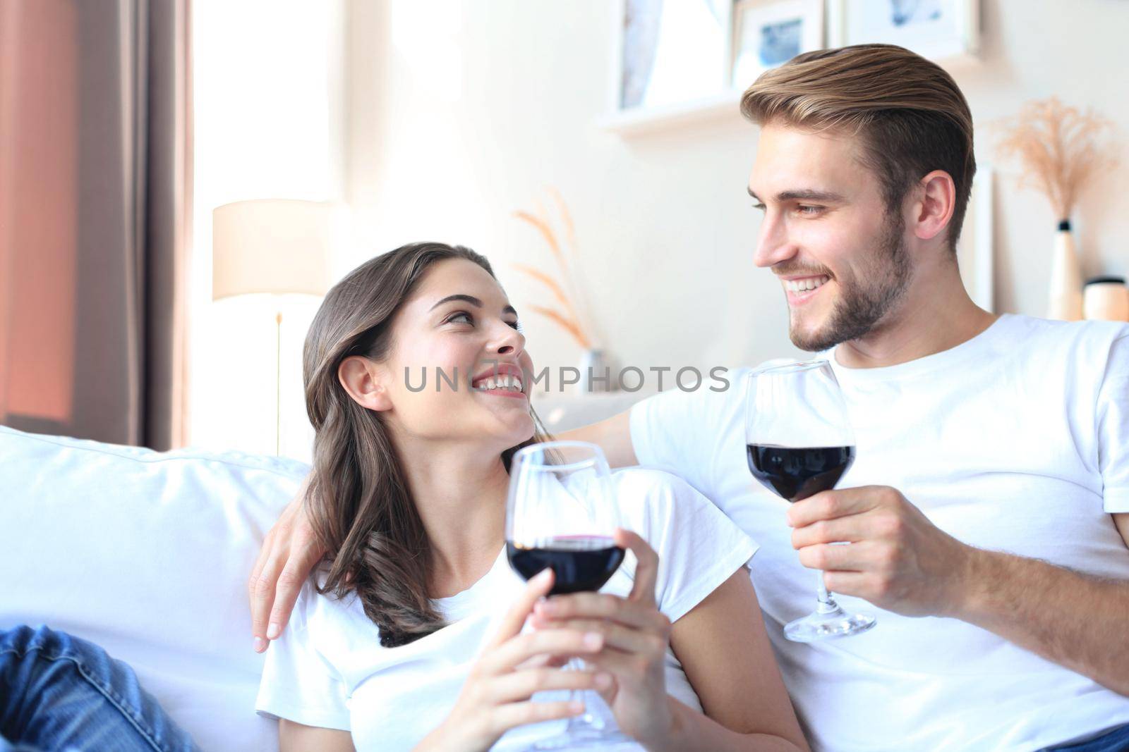 Young loving couple drinking a glass of red wine in their living room