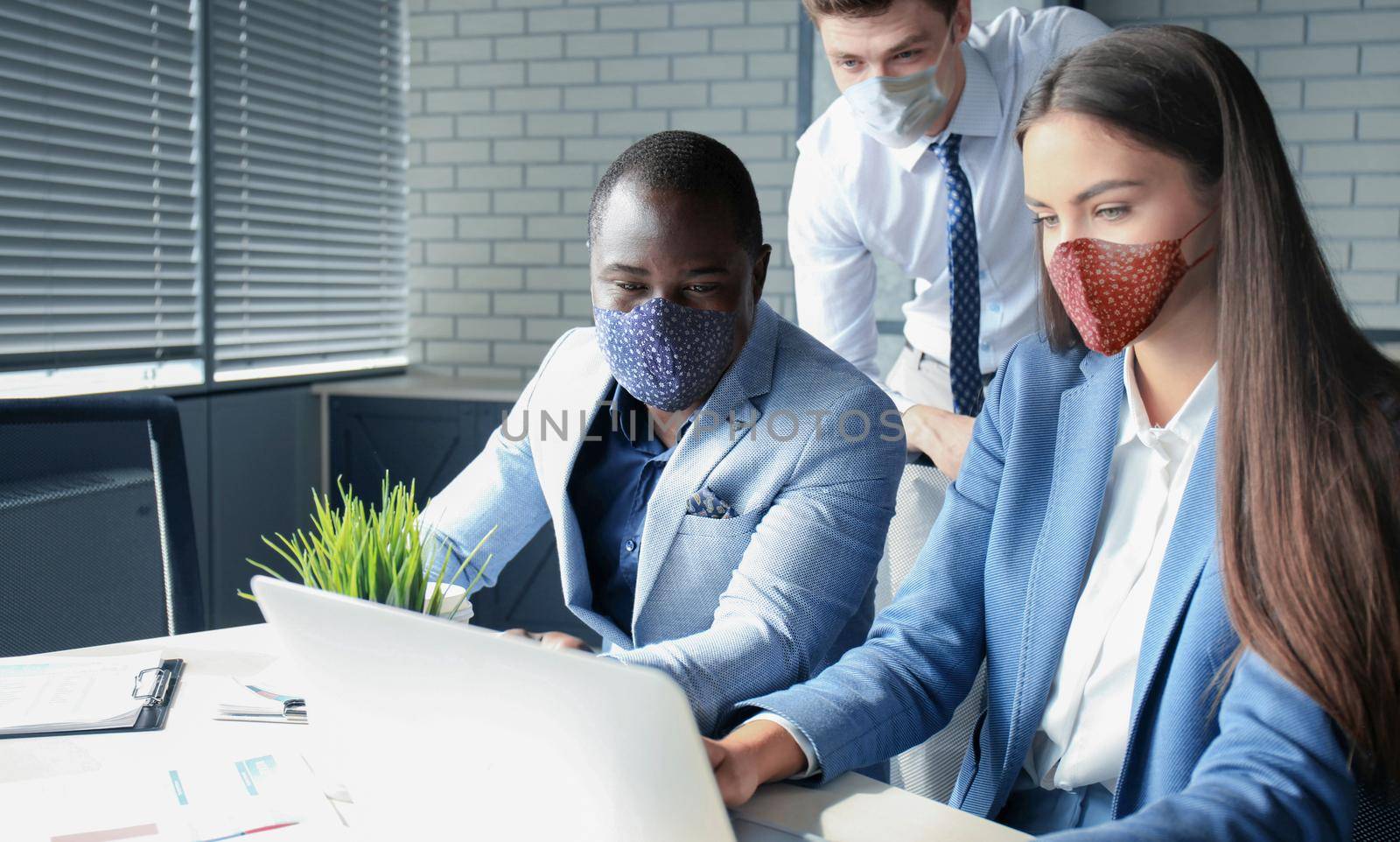 Business team in protective masks works in the office. by tsyhun