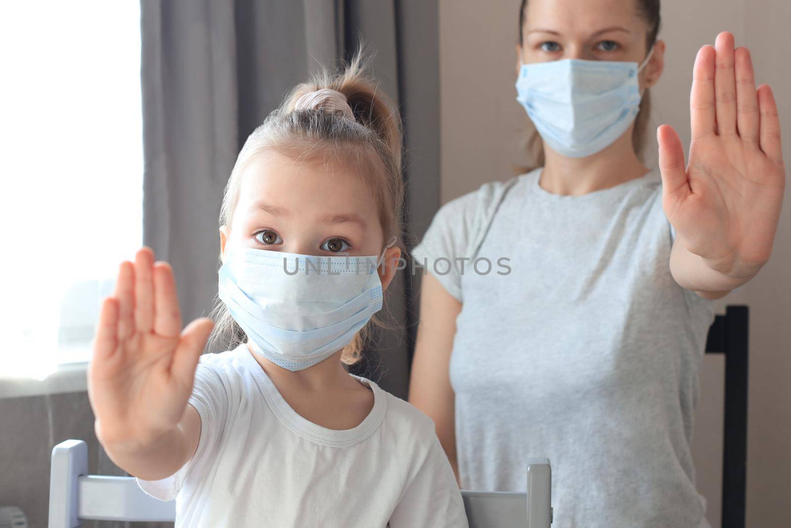 Little girl with mother in medical masks showing Stop of COVID-19 epidemic