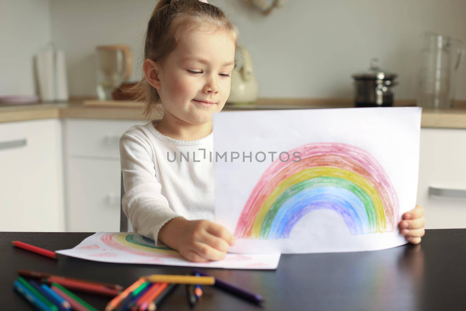 Girl painting rainbow at home, a symbol of UK National Health Service (NHS). Thanks to the doctors for their work. Stay at home Social media campaign