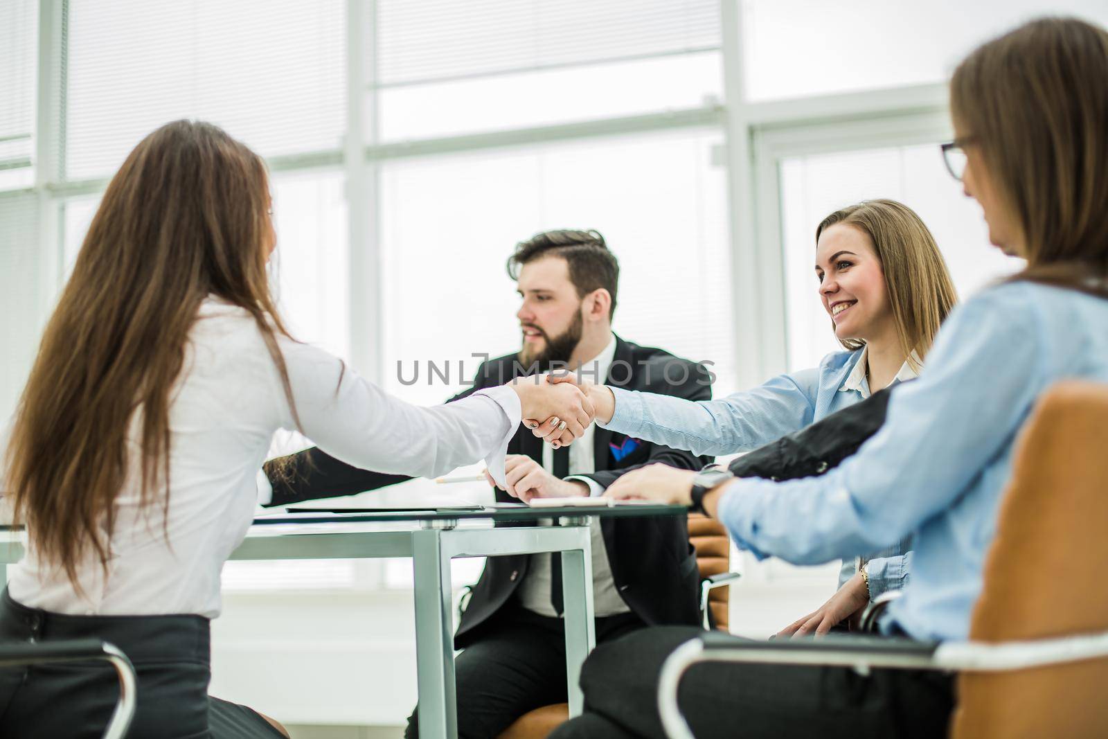 handshake business partners after discussing the terms of a new contract in the workplace in a modern office.the photo has a empty space for your text