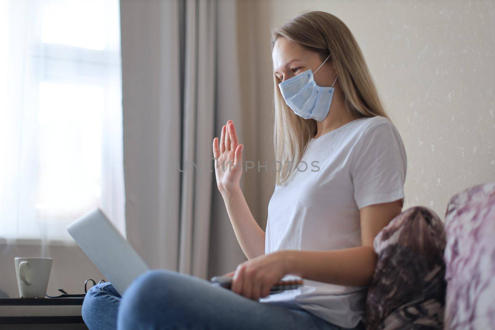 Young woman in medical mask doing video call with collegues from home during self isolation and quarantine. by tsyhun