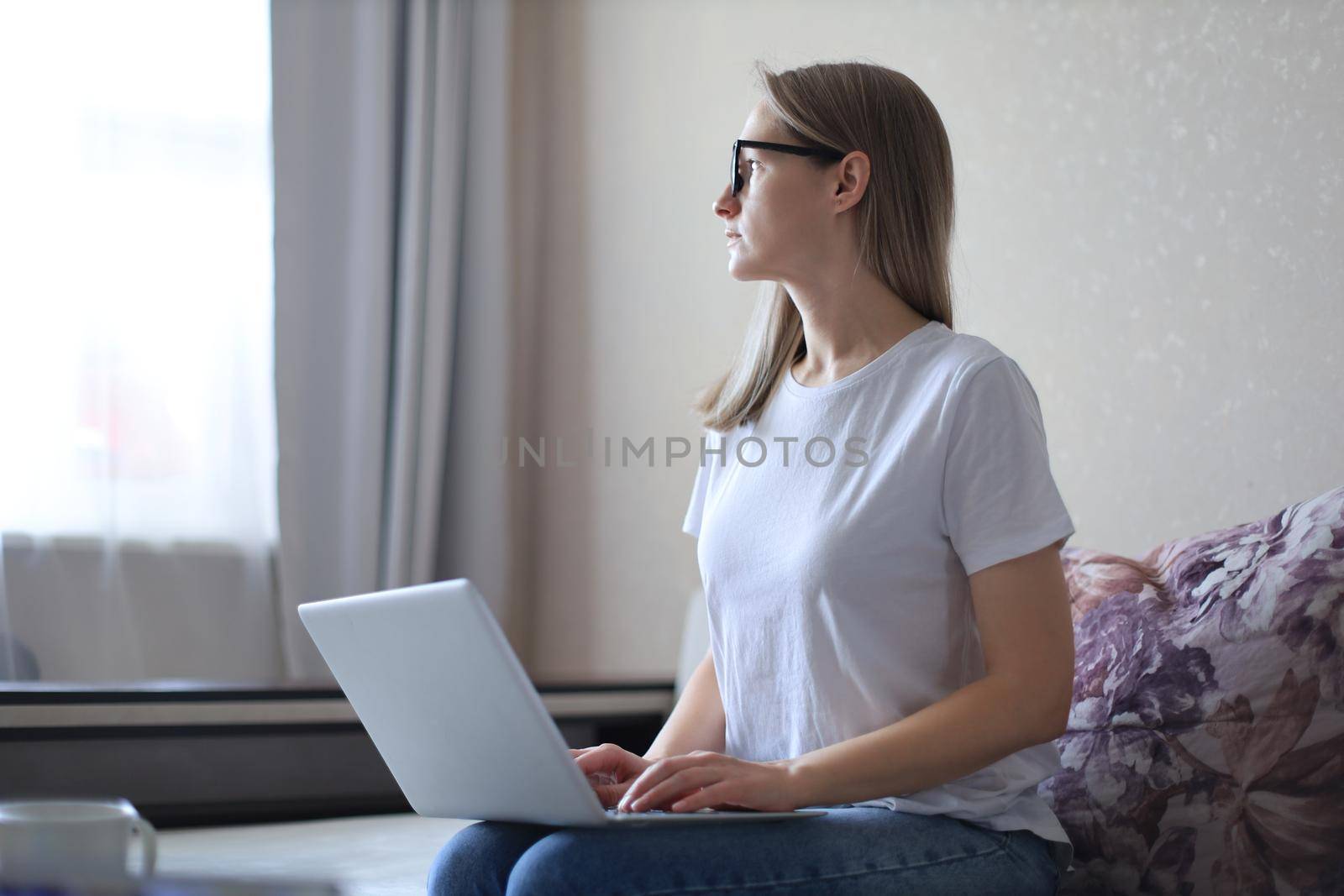 Young woman in medical mask works from home during self isolation and quarantine. Work online and stay at home. by tsyhun