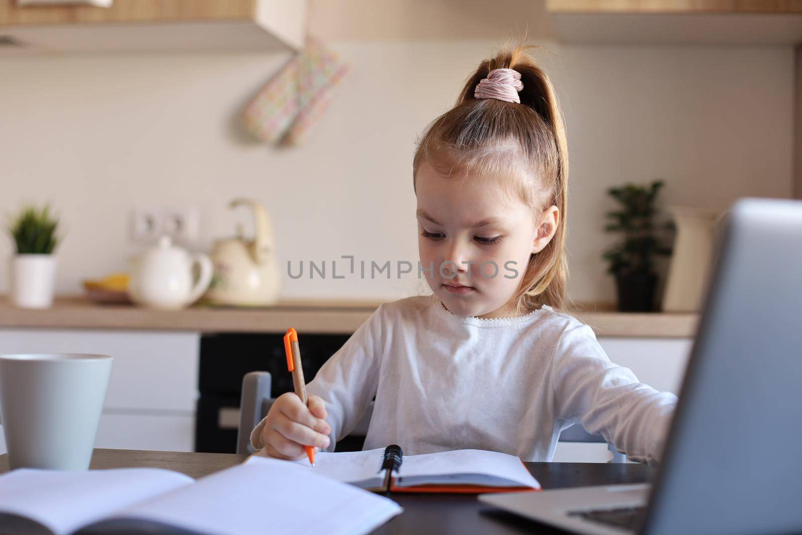 Serious little girl handwrite study online using laptop at home, cute happy small child take Internet web lesson or class on computer, homeschooling concept